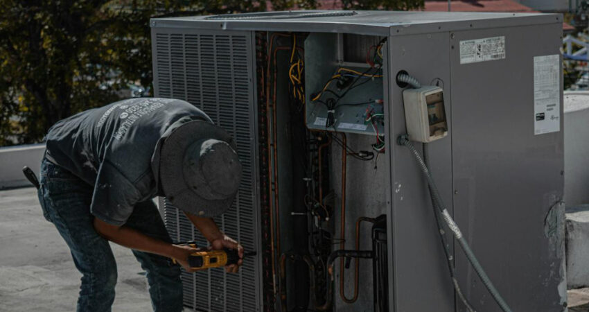 AC technician performing maintenance on an outdoor air conditioner unit.