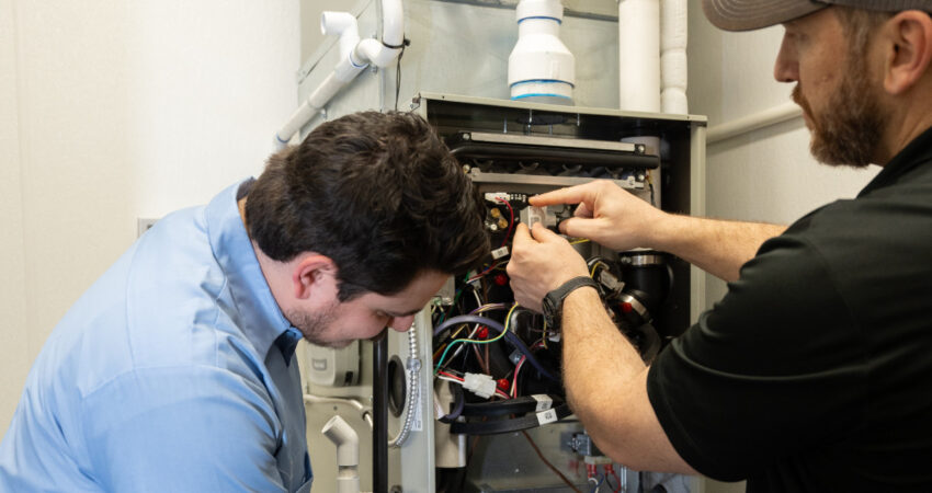 HVAC technicians perfroming repair on a furnace.